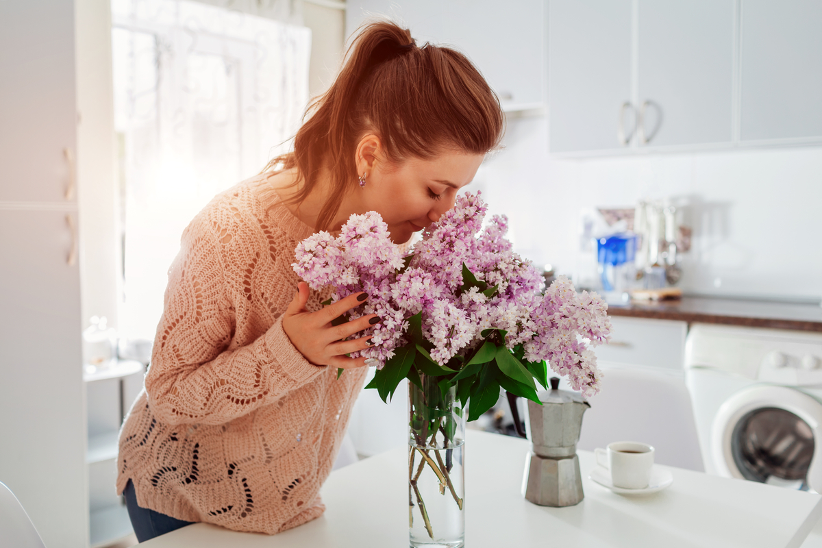 A woman smelling cut lilac flowers