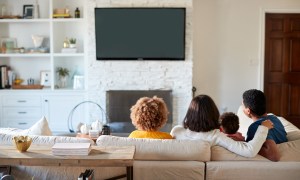 Family sitting on a couch watching tv.