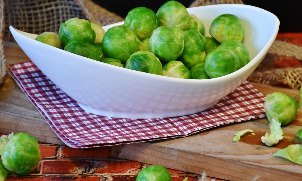 A gravy boat of Brussels sprouts on a cutting board