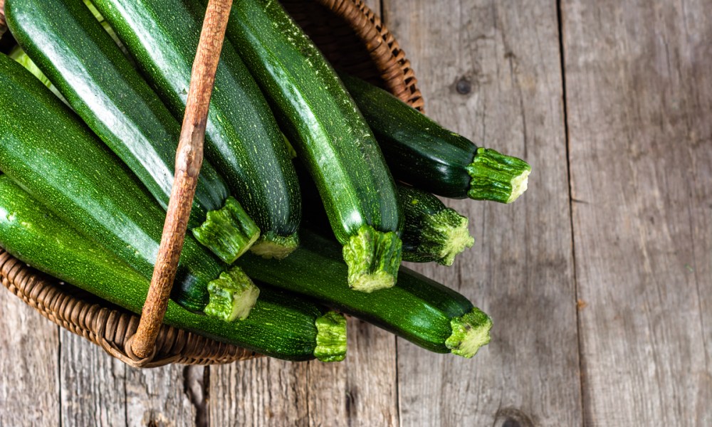 A basket of zucchini on a wooden table