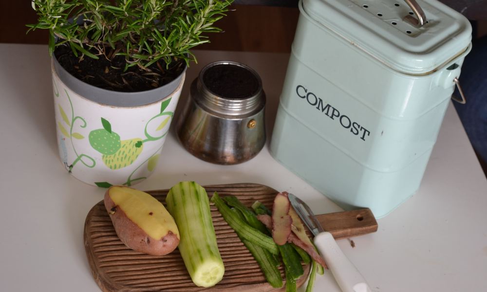 A small compost bin with food scraps next to it