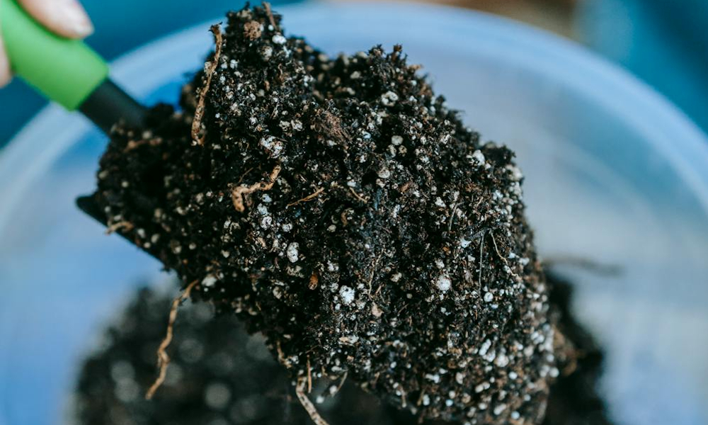 A garden shovel with potting soil, fertilizer, and perlite on it.